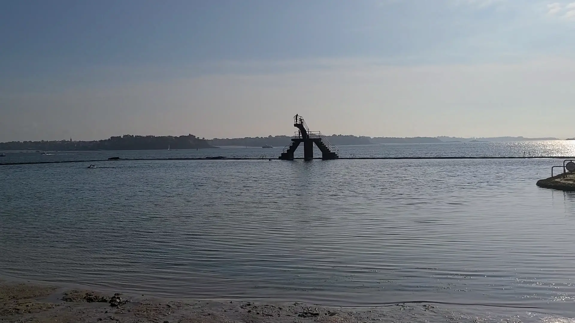 A diver leaping off the iconic diving platform at Piscine d'eau de mer de la plage Bon-Secours in Saint-Malo. 생말로의 Piscine d'eau de mer de la plage Bon-Secours에서 상징적인 다이빙대에서 점프하는 다이버.