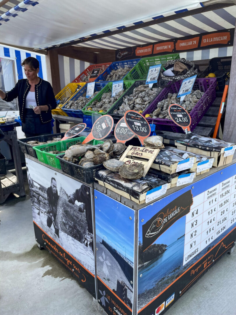 An oyster price board at marche aux huitres in Cancale, displaying various oyster types and prices. 캉칼 marche aux huitres 노점에 걸려 있는 굴 가격표