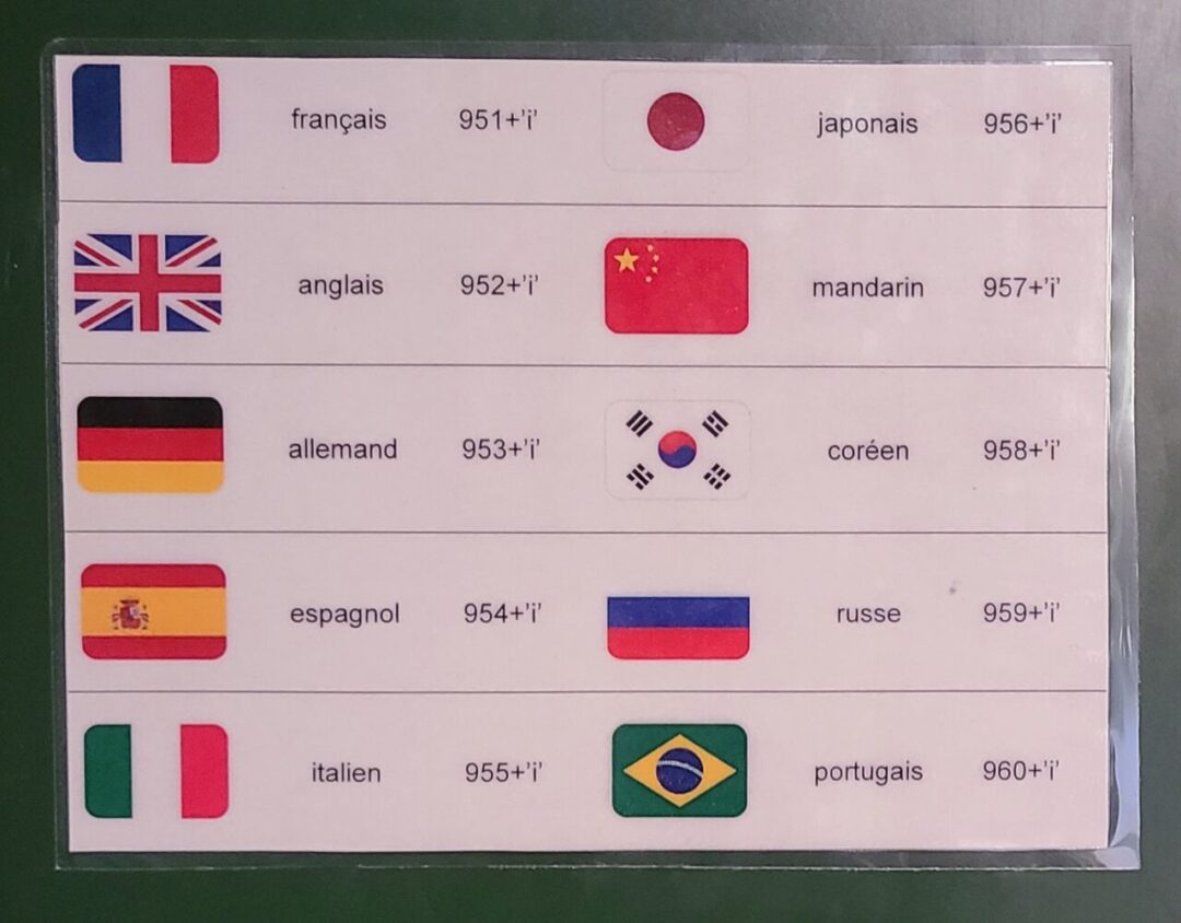 A sign displaying the available languages for the Mont Saint-Michel audio guide, including French, English, German, Spanish, Italian, Japanese, Mandarin, Korean, Russian, and Portuguese. 몽생미셸 오디오 가이드에서 지원하는 언어 목록을 보여주는 안내판으로, 프랑스어, 영어, 독일어, 스페인어, 이탈리아어, 일본어, 중국어, 한국어, 러시아어, 포르투갈어가 포함됨.