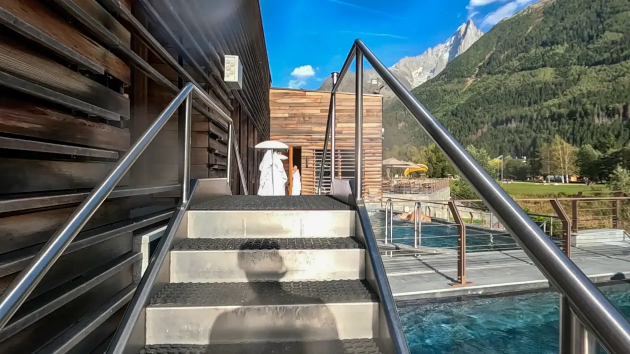 A small staircase leading to an intimate spa area at QC Terme Chamonix, with a scenic mountain view in the background. QC Terme Chamonix의 아담한 스파로 이어지는 작은 계단, 웅장한 산맥을 배경으로 한 풍경