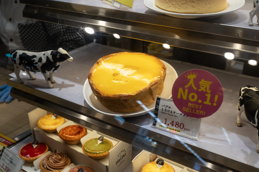 Whole-size PABLO cheese tart displayed at Shinsaibashi, Osaka, with a golden creamy filling. 오사카 신사이바시 파블로 매장에 진열된 정규 사이즈 치즈 타르트, 부드럽고 크리미한 필링이 특징