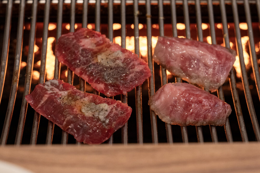 Garlic-marinated skirt steak grilling over flames. 갈릭 양념이 된 고기를 굽는 모습